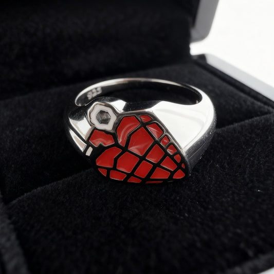 Close up eye-level shot of a custom red and black enamel grenade shape signet ring please on the inside of a black velvet ring box pad