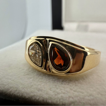 A close up shot of a custom gemstone ring in 18k yellow gold laid on a cream textured background