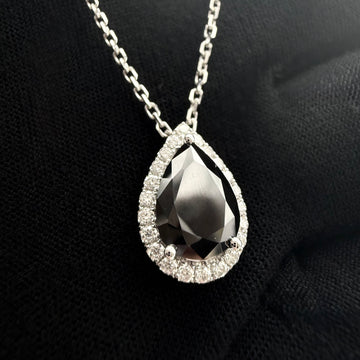 a Custom Made Black diamond pear drop pendant with a white diamond halo with a white gold cable chain on a black glove.