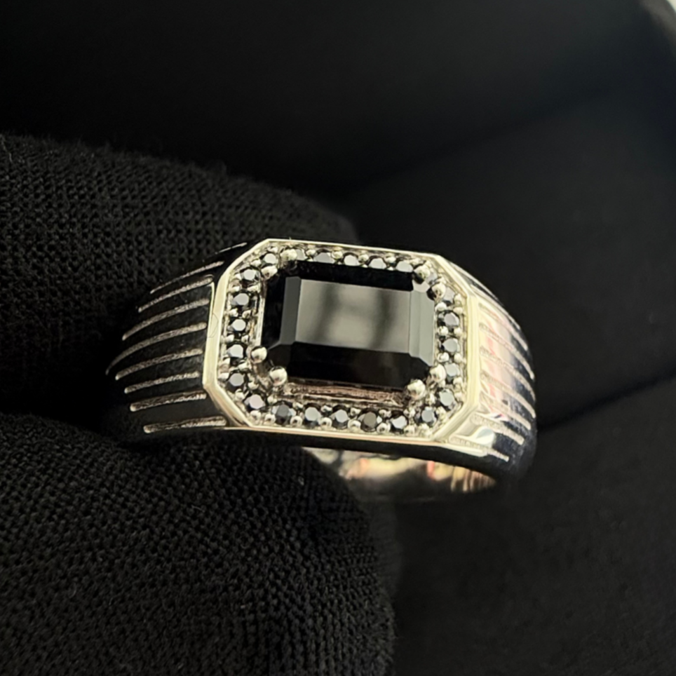 Close up of a black onyx signet ring in sterling silver with a black background