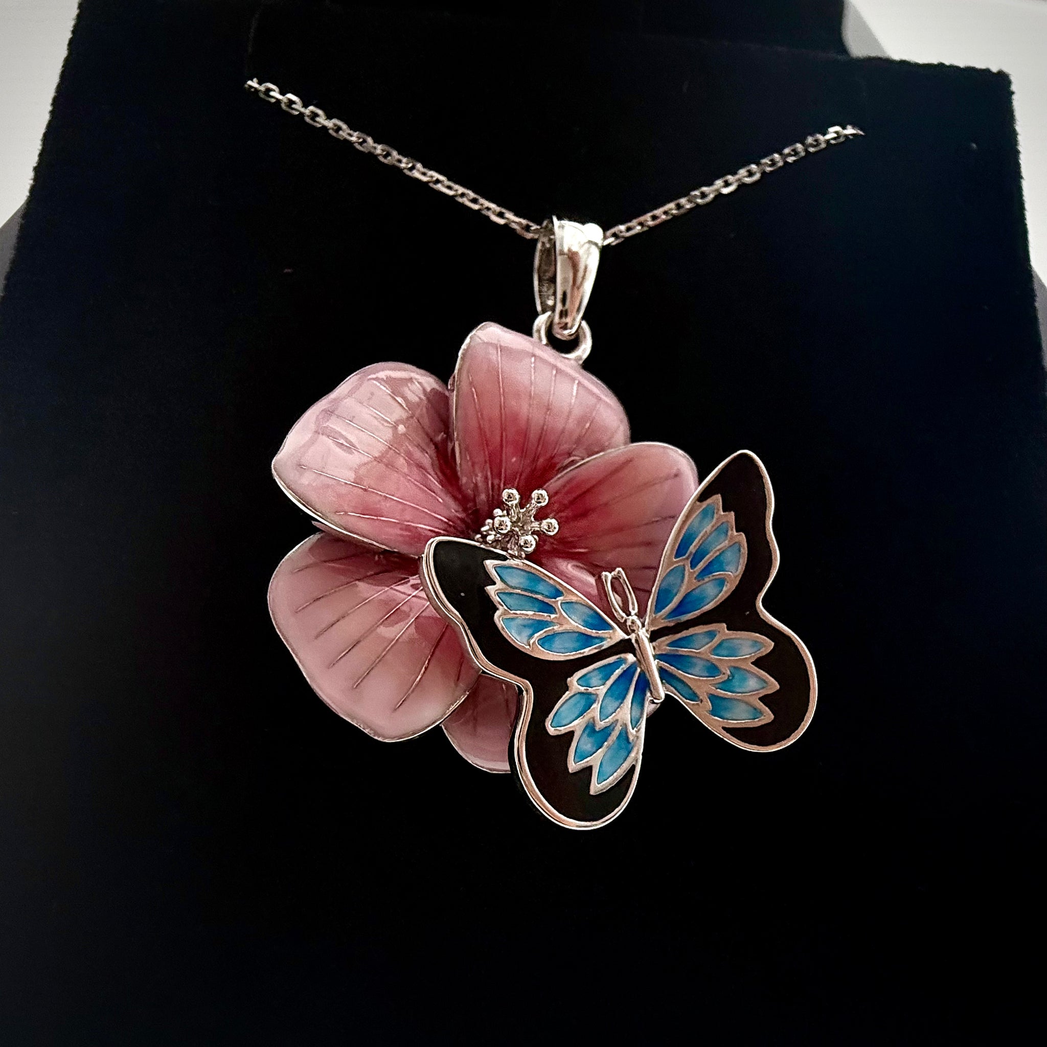 Front shot of a custom butterfly and flower pendant with a necklace on a black backrgound