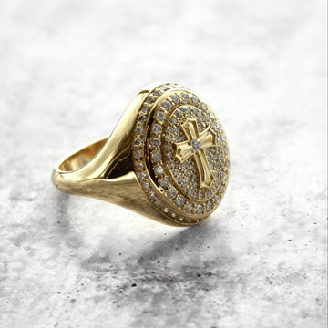 A close up eye-level shot of a Custom Gold Cross signet ring with natural diamond on a grey textured background