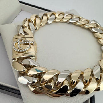A custom Gold Cuban chain bracelet with diamond clasp on a white cushion.