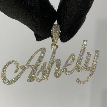 front angle photo of a Custom diamond Name pendant "ashley" being held by a black glove on a white background