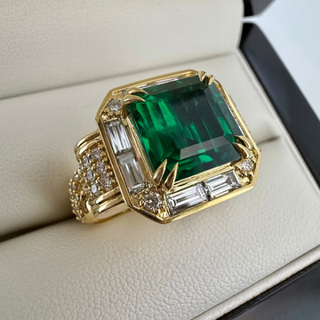 Gold ring with a green gemstone on a beige surface