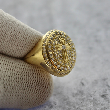 a close up of a custom white diamond cross signet ring in yellow gold with a grey textured background