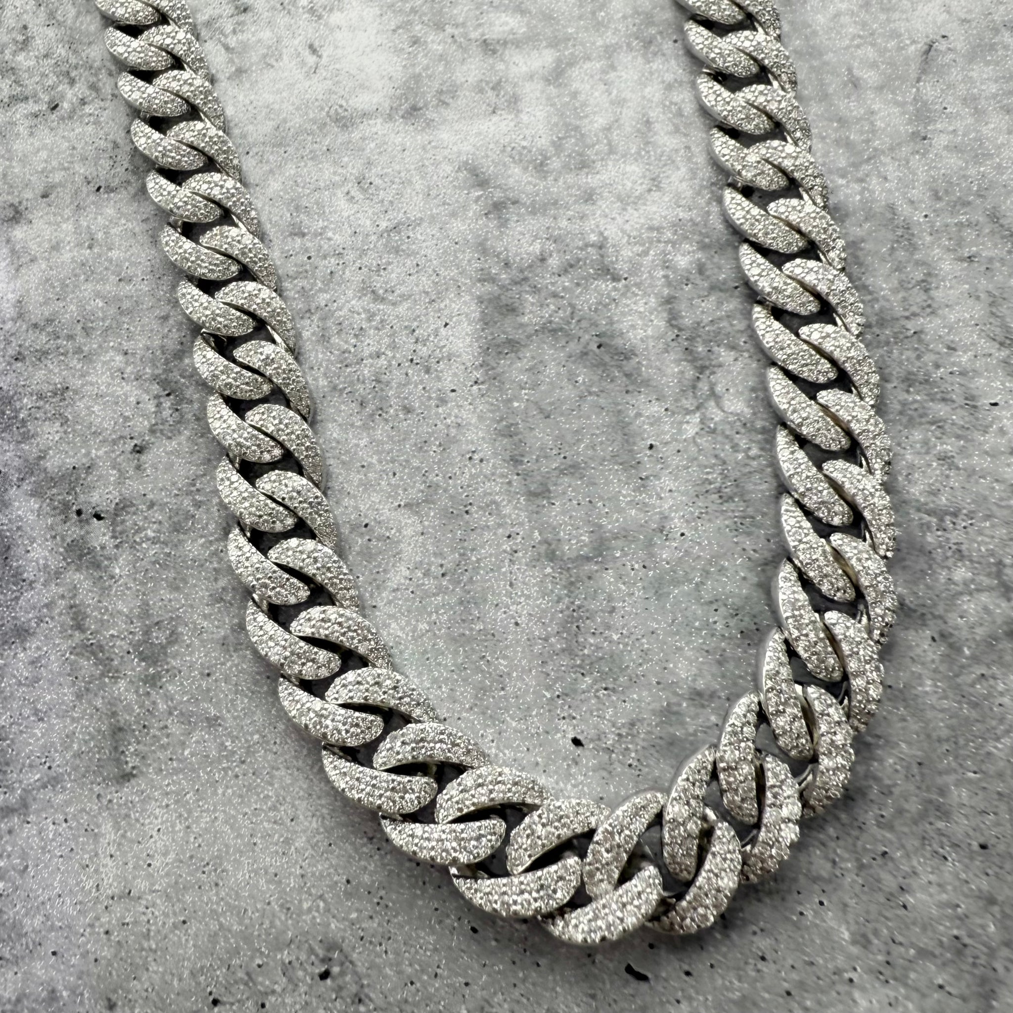A Custom Iced out Diamond Silver chain necklace on a textured grey surface
