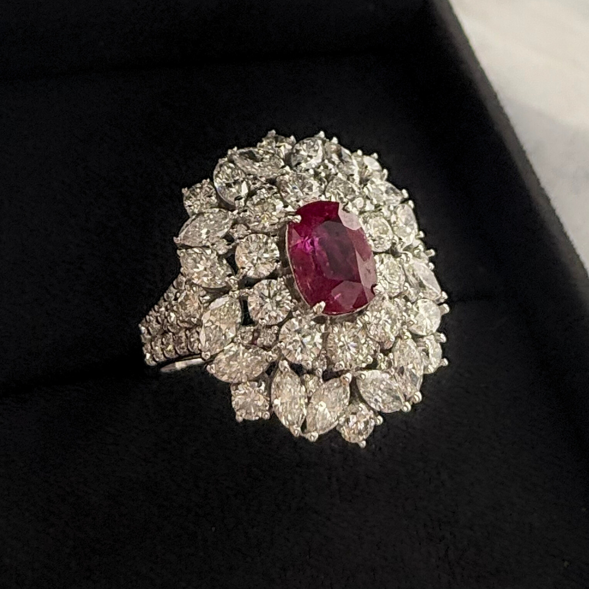 Top angle close up shot of a natural ruby and diamond cluster gemstone ring with a black background