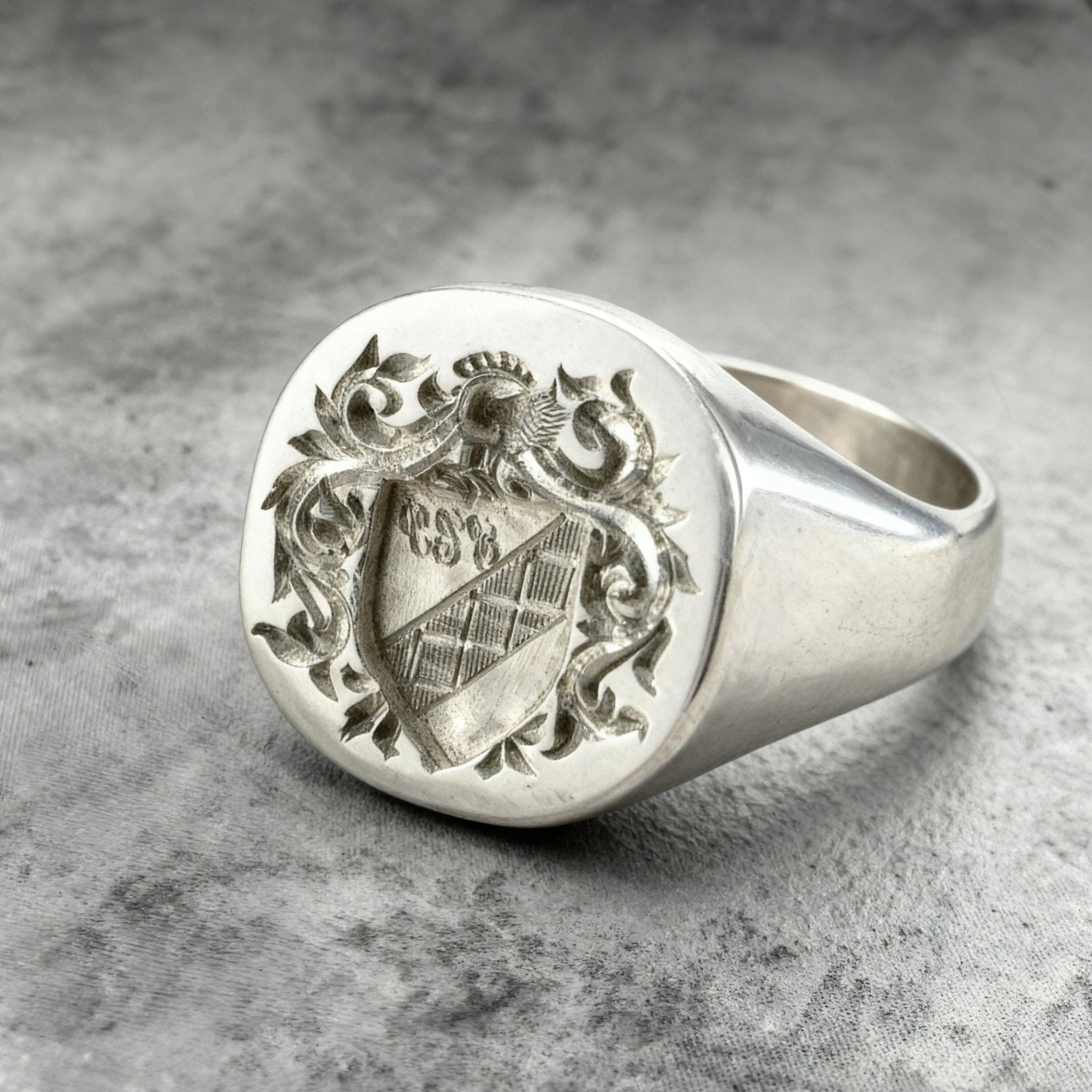 Close up shot of a Sterling silver custom Family Crest, Coat of arms signet ring on a grey background