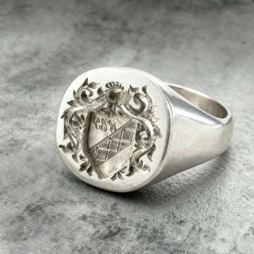 Close up shot of a Sterling silver custom Family Crest, Coat of arms signet ring on a grey background