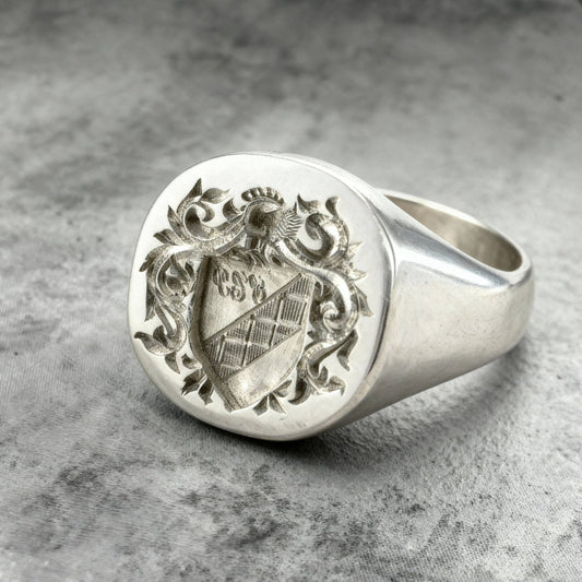 Close up shot of a Sterling silver custom Family Crest, Coat of arms signet ring on a grey background
