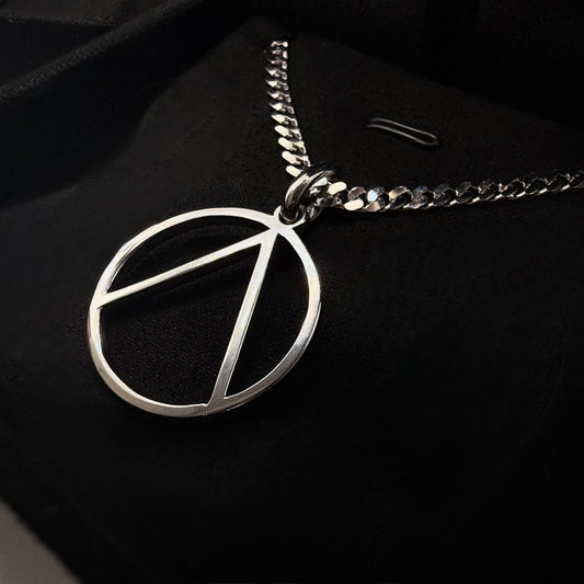 close up top angle shot of a custom symbol logo pendant laid on a black background