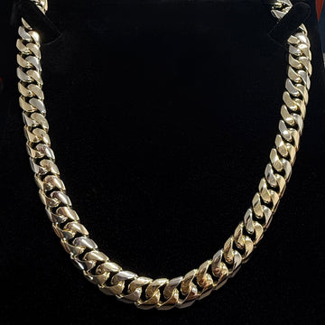 Front on shot of a custom 12mm cuban link chain in solid 9k gold on. a black background