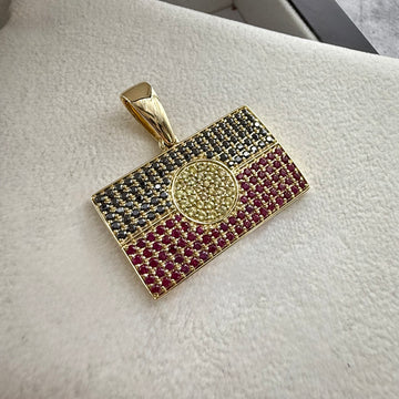 top angle shot of a custom made natural gemstone aboriginal flag pendant laid on a cream textured background